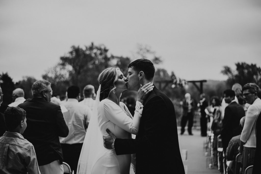 Bride and groom kissing at the end of the aisle at their ceremony. 