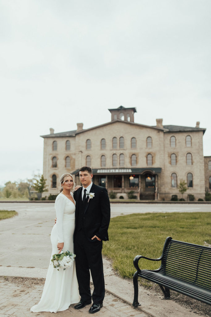 Bride and groom standing in front of their elegant wedding venue, the Dousman House in Wisconsin.