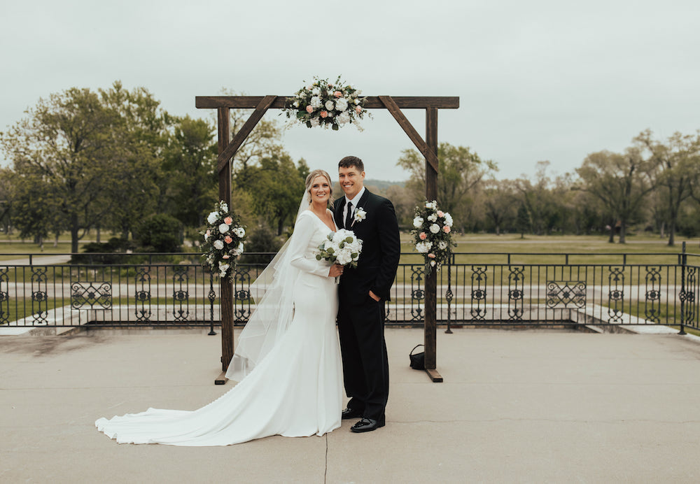 Elegant bride and groom standing in front of their wedding arch at the Dousman House in WI.