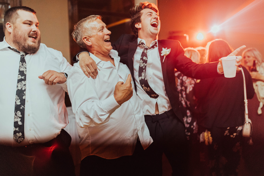 Wedding guests dancing under bright lights at a wedding reception.