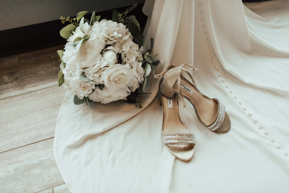 Wedding detail shot with bouquet, shoes and the train of the brides wedding dress.