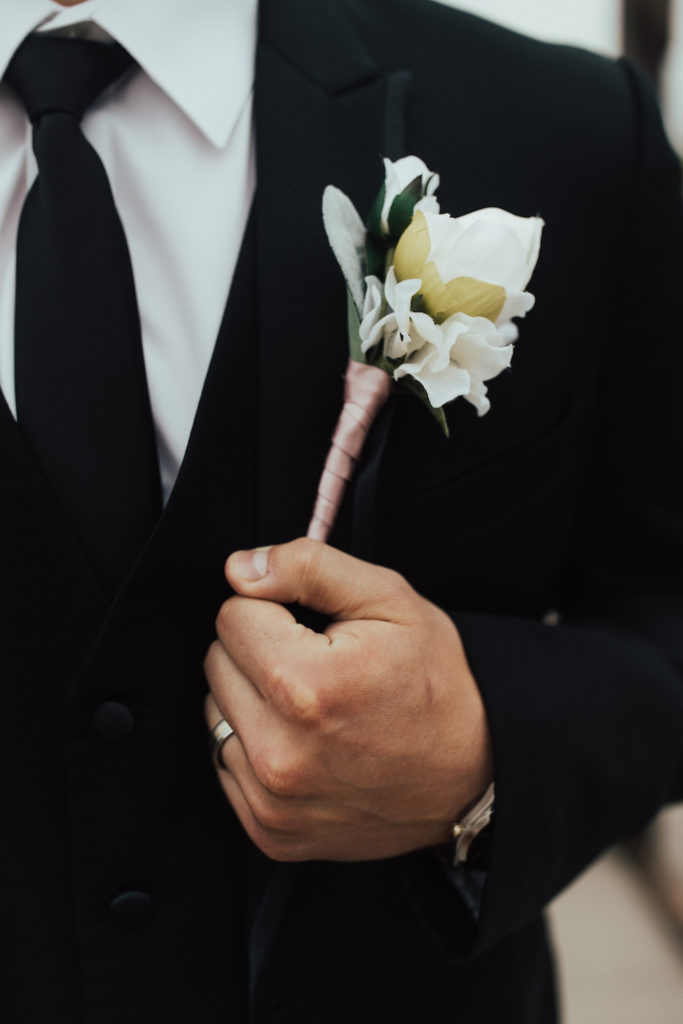 Upclose shot of the groom wearing a black tux and a white boutonniere. 