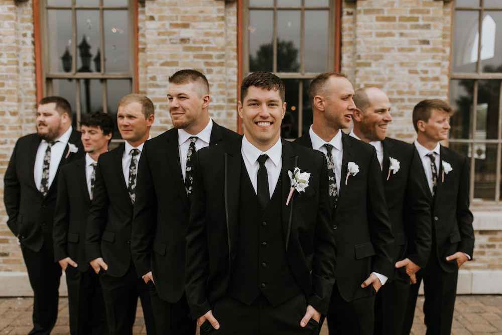 Groom and his groomsmen wearing all black suits and black ties. 