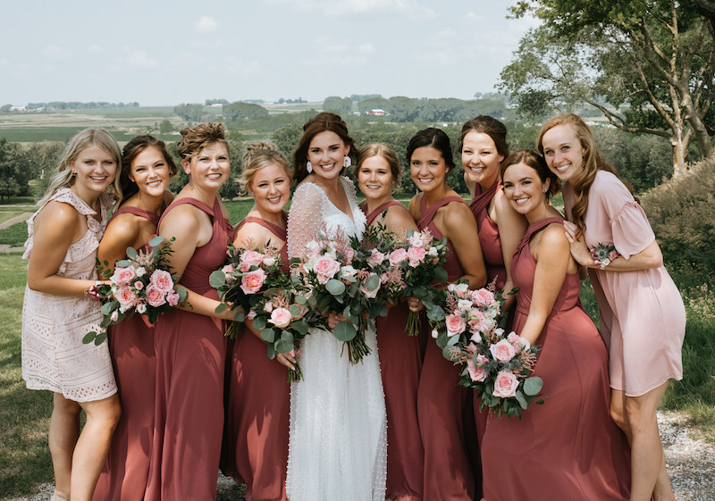Burgundy and pin bridesmaid dresses holding pink rose bouquets. 