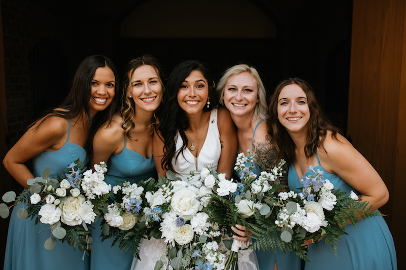Bride and her bridesmaids wearing teal spaghetti strap dresses and matching bouquets. 