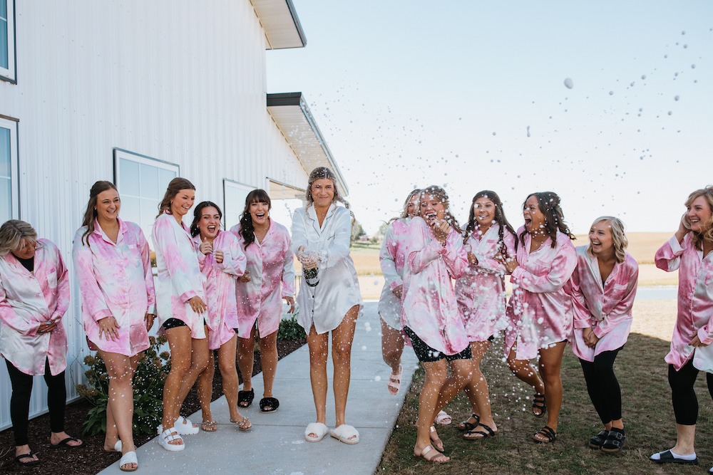 Bride and bridesmaids champagne pop in matching pink pajamas. 