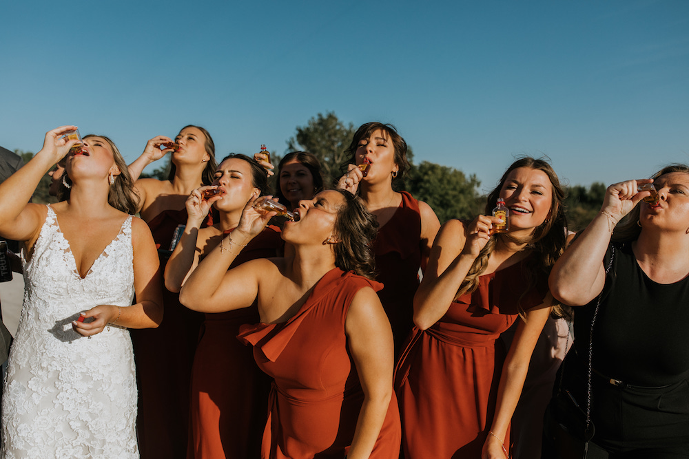 Bride and bridesmaids taking shots of fireball before the wedding reception. 