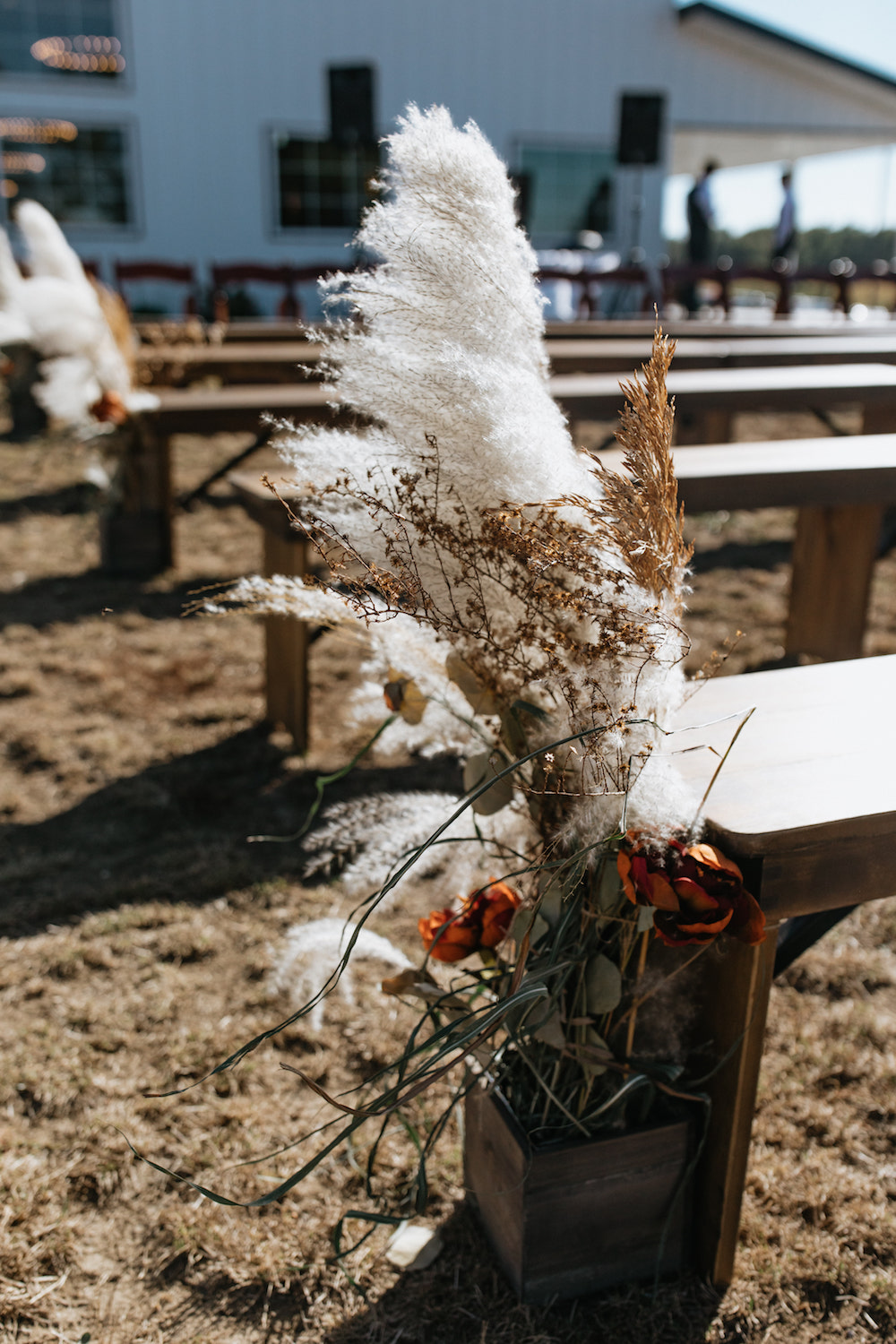 Boho wedding aisle decor with pampas grass and other fall colored flowers. 